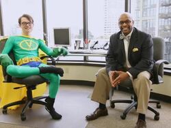 MS PAN Man dressing as superhero in green outfit and yellow cape and business man sitting in office and Smiling  / Seattle, Washington, United States  Stock Footage