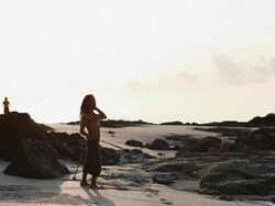 MS Rasta man spinning poi balls on beach with lady jogging and ocean break and sunrise / Montezuma, Punteranes, Costa Rica Stock Footage