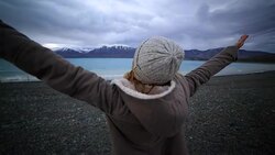 Young woman by the lakeshore arms outstretched Stock Footage