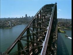 WA boat moving through calm water to Harbour bridge, early morning sun behind it, City skyline on horizon, Australia Stock Footage