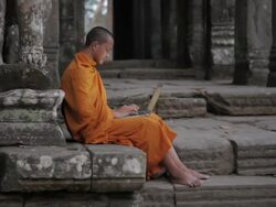 WS, PAN A Buddhist monk uses a laptop computer on the steps of an ancient temple in Angkor Wat / Siem Reap, Cambodia Stock Footage