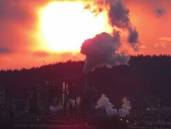 Extreme large sunset set against a polluting smokestack of an oil refinery Stock Footage