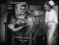 B/W 1948 man with polio in iron lung talking into mirror / nurse adjusts controls on iron lung Stock Footage