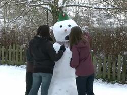 MS Woman putting dry leaves for making snowman mouth / Saarburg, Rhineland-Palatinate, Germany Stock Footage