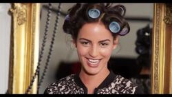 A woman with her hair in rollers blows a kiss to camera Stock Footage
