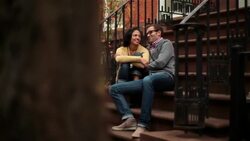 New York couple talk and laugh on stoop of brownstone apartment (dolly-shot) Stock Footage