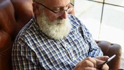 elderly professor is typing a message on a smartphone Stock Footage