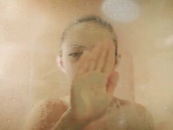 Young girl wiping water from shower door Stock Footage