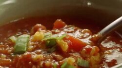table spoon dips into chili bowl topped by shredded cheese and mint leaves and scoops out a bite Stock Footage