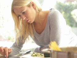Female in kitchen preparing food and looking at ipad Stock Footage
