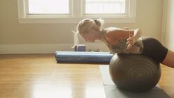 A mature woman doing situps with an exercise ball in her home gym. Stock Footage