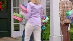 Excited grandmother welcomes family home for the holidays, hugs everyone, and stoops to talk with grandchildren (dolly-shot) Stock Footage