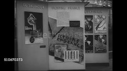 1943: ROCKEFELLER PLAZA EXHIBIT: HD: WS Three freestanding information panels in the United Nations Exhibition sponsored by the United States Office of War Information (OWI), people walking through frame FG.   El Salvador, Fighting France, Guatemala Instructional Video