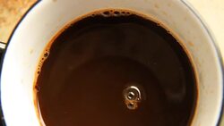 Close view from the top of the coffee is poured into a cup of coffee. Stock Footage