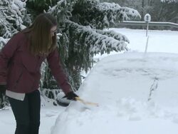  MS Young woman removing snow from car with brush / Saarburg, Rhineland-Palatinate, Germany Stock Footage