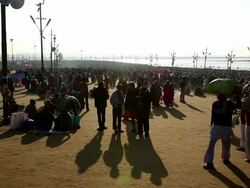 People mill about in foreground of vast crowd stretching to banks of the river Ganges, Kumbh Mela, India Stock Footage