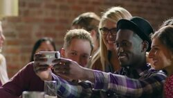 Group of friends take selfie with smartphone in crowded bar Stock Footage