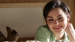 young woman lying on motel bed turns and smiles at camera Stock Footage