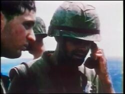 1960s close up soldier in helmet talking on telephone outdoors / other soldiers around him / Vietnam War Stock Footage