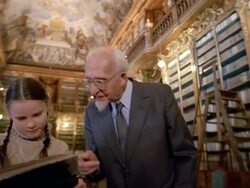 Low angle medium shot girl and grandfather reading book in Philosophical Hall library at Strahov Monastery / Prague Stock Footage