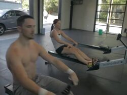 Close-up on Tyler as he works out on rowing maching; Jill rows in the background. Stock Footage
