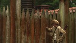 A man in pioneer clothing enters a rustic gate. Stock Footage