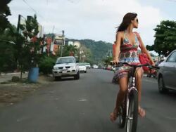 woman in a dress and sunglasses riding a bike down the street Stock Footage