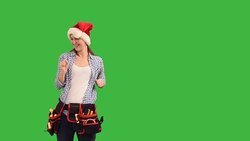 slender young woman construction worker in a cap of Santa Claus on a green background Stock Footage