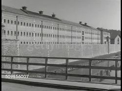 1946: FRANCE PRISON: WS Prison building (possibly Helun prison), French guard walking over bridge. WS Prisoners marching in line, officer shouting. HA INT WS Prisoners working in shop, sewing machines, guard. WS Prisoners sewing at machines. Justice Instructional Video