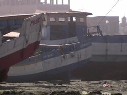 "Colourful wooden boats sitting on sandy beach, sand blowing around, buildings visible in b/g, Trujillo, Peru [PerÃƒÂº]" Stock Footage