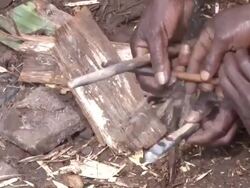 CU TS Man making small ember on  piece of dry wood and woman smoking ashes / kigez, kabale, uganda Stock Footage