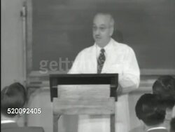 1951: MENNINGER INSTITUTE: Dr. Karl A. Menninger (1893-1990) lecturing in front of class. Dr. Karl A. Menninger standing behind podium. Doctors & psychiatric personnel in classroom setting, sitting, listening, looking forward left. Instructional Video