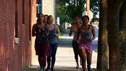 MS Group of women running on sidewalk of city street at sunrise Stock Footage