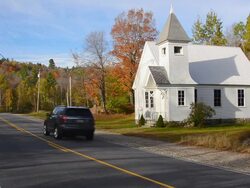 WS Shot of Newry Community Church 1904 in Northern New England in fall foliage in October with car traveling on road / Newry, Maine, United States Stock Footage