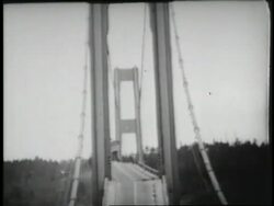 The Tacoma Narrows Bridge twists and buckles in high winds, then collapses into the river. Stock Footage