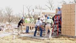 Diverse group of volunteers raise beam on home built for charity Stock Footage