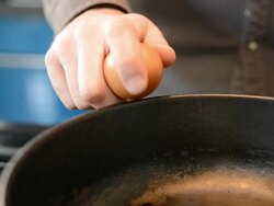 CU Shot of Egg being cracked into frying pan / London, Greater London, United Kingdom Stock Footage