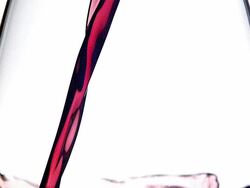 ECU SLO MO Red wine pouring into glass against white background / Vieux Pont, Normandy, France Stock Footage