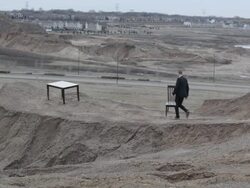 WS Young businessman in black suit bringing  chair out to  table on top of  bluff in  rural area / Maple Grove, Minnesota, United States Stock Footage