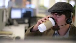 Trendy office worker in cubicle with headset sips coffee Stock Footage