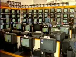 ARCHIVAL Time lapse - MCU people walking in front of bank of television screens in Electrical Goods Store Stock Footage