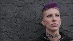 Cool tough young woman with purple hair, neck tattoo and lip piercing Stock Footage
