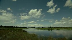 Clouds race above a river and grasslands. Stock Footage