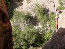 Handheld tilt of a man climbing a rock wall in the sunshine. Stock Footage