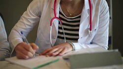 Doctor using tablet and writing a prescription Stock Footage