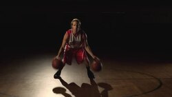 A basketball player displays his dribbling technique with two basketballs at center court of a gymnasium. Stock Footage