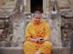 MS, PAN A Buddhist monk taps on the screen of a smartphone on an ancient temple in Angkor Wat / Siem Reap, Cambodia Stock Footage