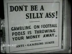 1937: LONDON, ENGLAND: LA WS Street in London w/ double-decker bus & people walking FG. MS Anti-Gambling League poster. John Gulland at desk saying children are taught to bet, setting them on 'gambling way', leads to economic, moral disintegration. Instructional Video