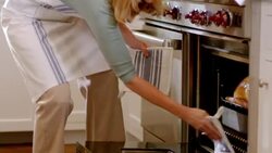Housewife enters kitchen, takes turkey out of oven and smells (dolly-shot) Stock Footage