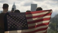 Young woman holds up American flag while friends look out and take smartphone photos of Austin, Texas skyline Stock Footage